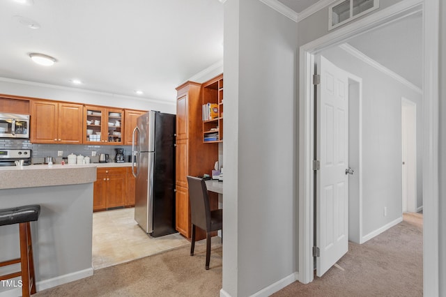 kitchen featuring light countertops, visible vents, appliances with stainless steel finishes, ornamental molding, and light carpet