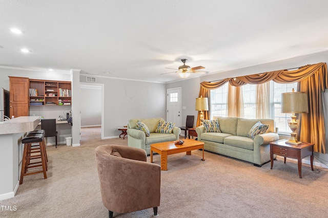 living area featuring light colored carpet, a healthy amount of sunlight, visible vents, and crown molding