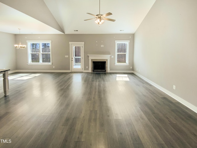 unfurnished living room featuring dark wood-type flooring, lofted ceiling, a fireplace, and ceiling fan with notable chandelier