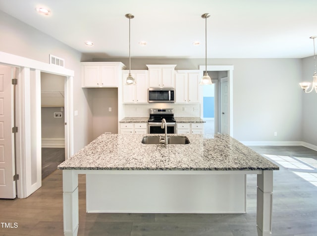 kitchen with wood finished floors, a kitchen island with sink, stainless steel appliances, white cabinetry, and a sink