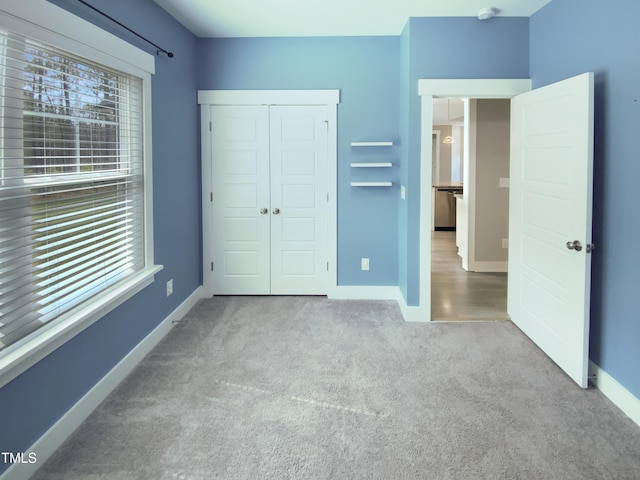 unfurnished bedroom with a closet, multiple windows, baseboards, and carpet flooring