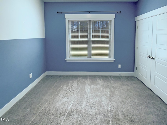 carpeted spare room featuring baseboards