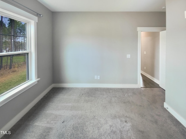 carpeted spare room featuring a healthy amount of sunlight and baseboards