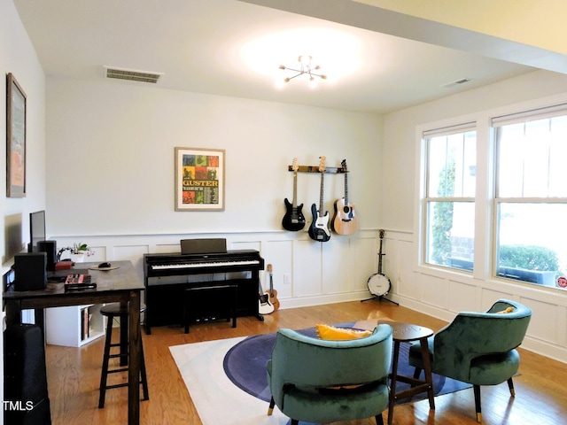 living area with visible vents, wood finished floors, and wainscoting