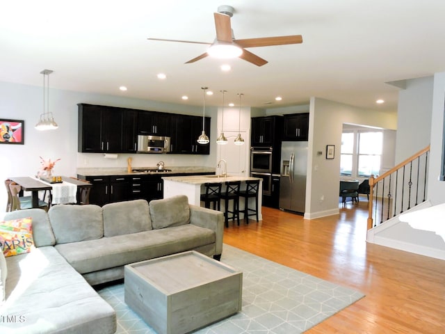 living area with light wood-style floors, recessed lighting, baseboards, and stairs