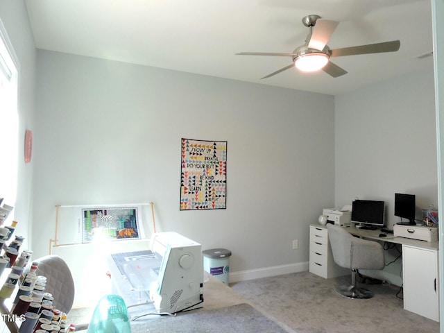 carpeted office space featuring baseboards and a ceiling fan