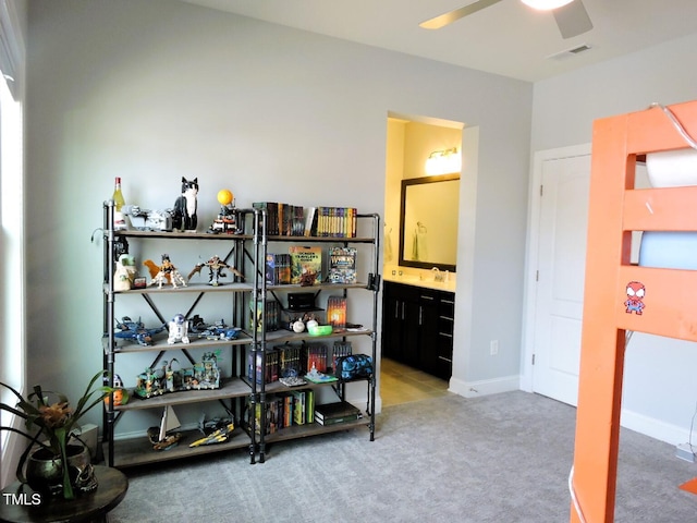 interior space with ceiling fan, visible vents, baseboards, and light colored carpet