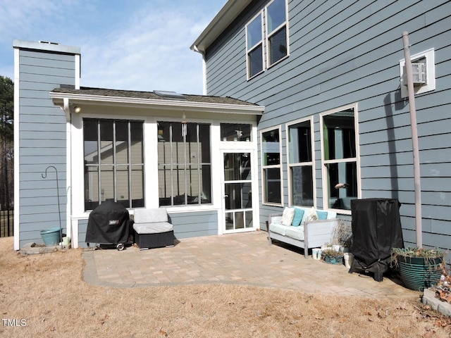 rear view of house featuring a patio area, a chimney, and a sunroom