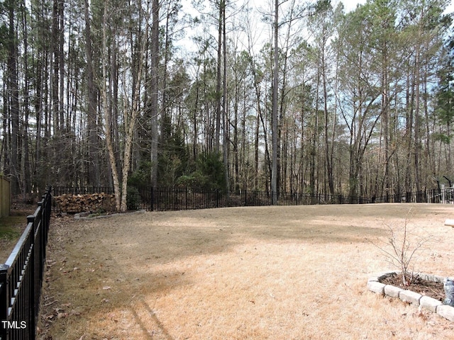 view of yard featuring a forest view and fence