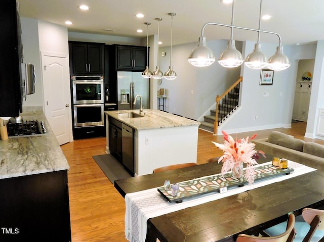 kitchen with stainless steel appliances, recessed lighting, light wood-style floors, a kitchen island with sink, and a sink