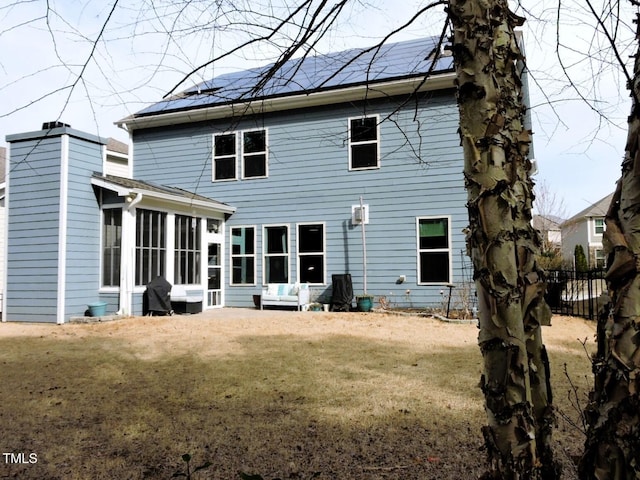 rear view of property featuring a sunroom, fence, a chimney, and a lawn