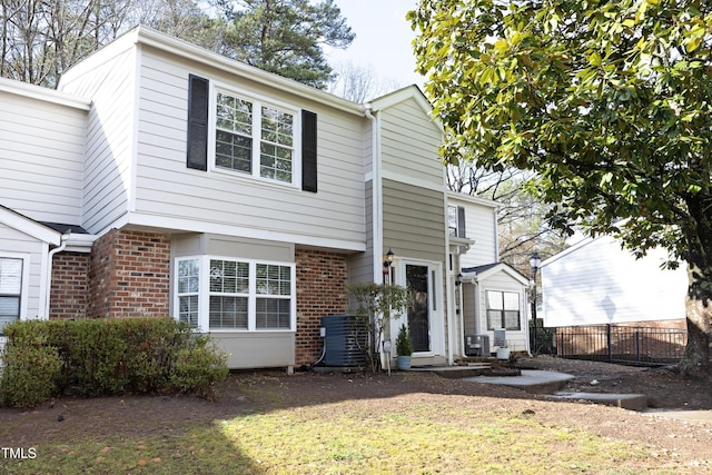 view of front of house with brick siding, fence, and central air condition unit