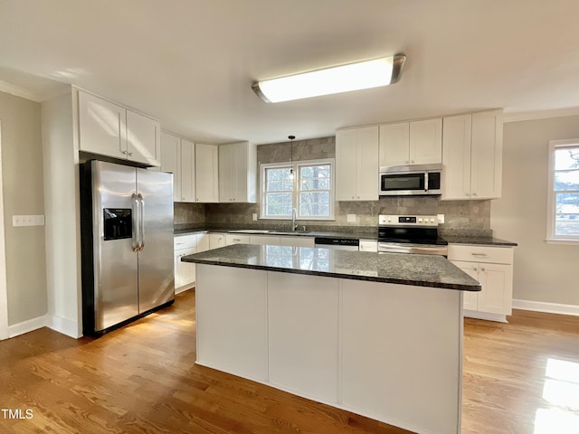 kitchen featuring a wealth of natural light, appliances with stainless steel finishes, light wood finished floors, and backsplash