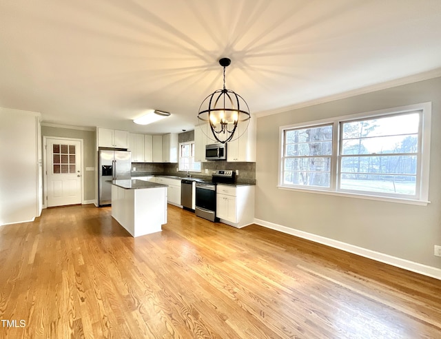 kitchen featuring a kitchen island, stainless steel appliances, light wood-style floors, white cabinetry, and backsplash