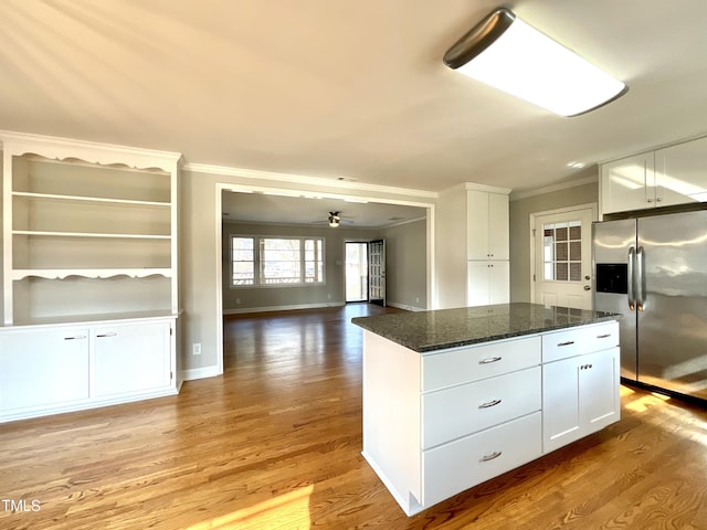 kitchen with stainless steel refrigerator with ice dispenser, ornamental molding, open floor plan, white cabinets, and light wood-type flooring