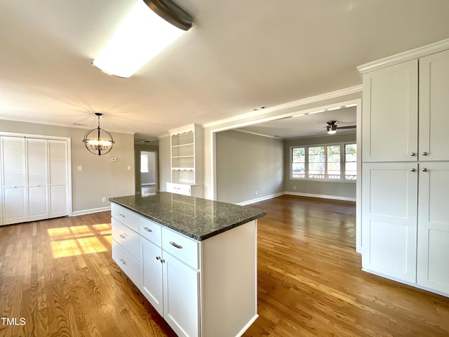 kitchen featuring a kitchen island, baseboards, white cabinets, and wood finished floors