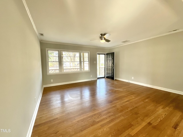 unfurnished room with wood finished floors, a ceiling fan, visible vents, baseboards, and ornamental molding