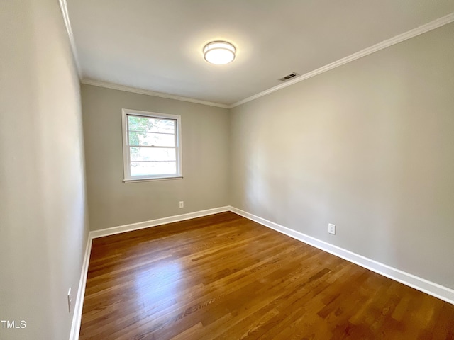 spare room with baseboards, crown molding, visible vents, and dark wood-type flooring