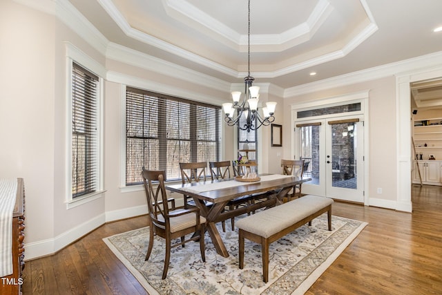 dining space featuring baseboards, french doors, an inviting chandelier, hardwood / wood-style flooring, and a raised ceiling