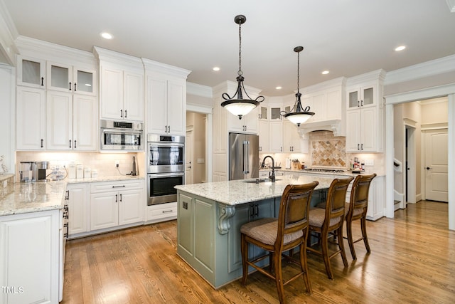 kitchen with crown molding, white cabinets, a kitchen island with sink, and stainless steel appliances