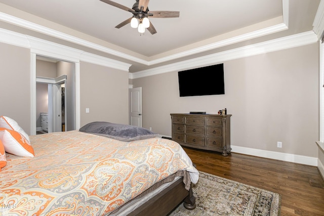 bedroom with ornamental molding, a ceiling fan, a tray ceiling, wood finished floors, and baseboards