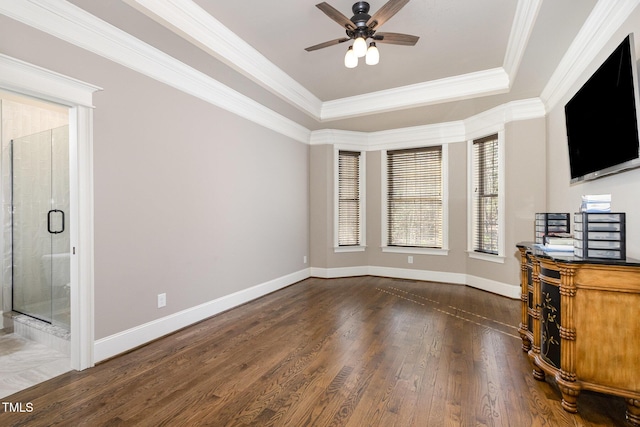 unfurnished living room featuring a ceiling fan, baseboards, dark wood finished floors, a tray ceiling, and ornamental molding