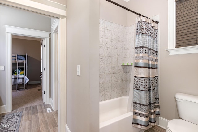 full bathroom featuring toilet, wood finished floors, shower / bath combo, and baseboards