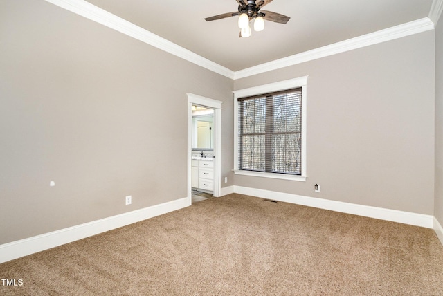 carpeted spare room featuring baseboards, crown molding, and a ceiling fan