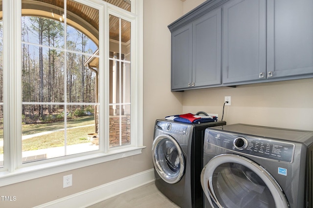 laundry room with cabinet space, independent washer and dryer, and baseboards