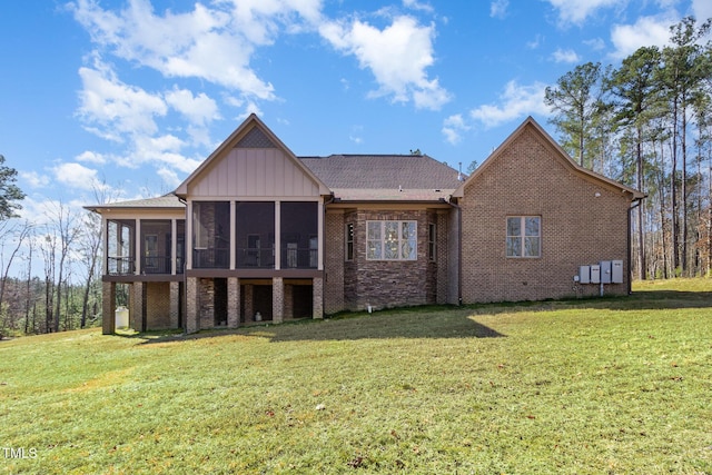 rear view of property featuring brick siding, board and batten siding, a yard, and a sunroom