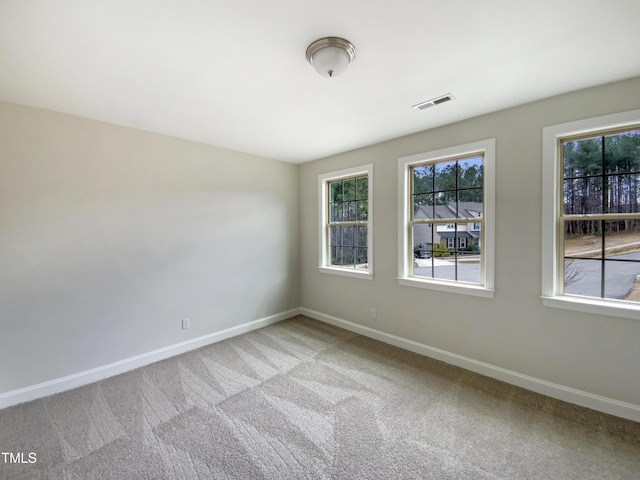 empty room featuring baseboards, visible vents, and light colored carpet