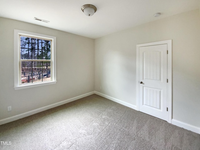 unfurnished room with carpet floors, visible vents, and baseboards