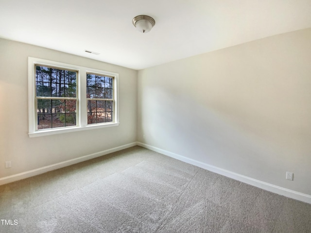 carpeted spare room featuring visible vents and baseboards