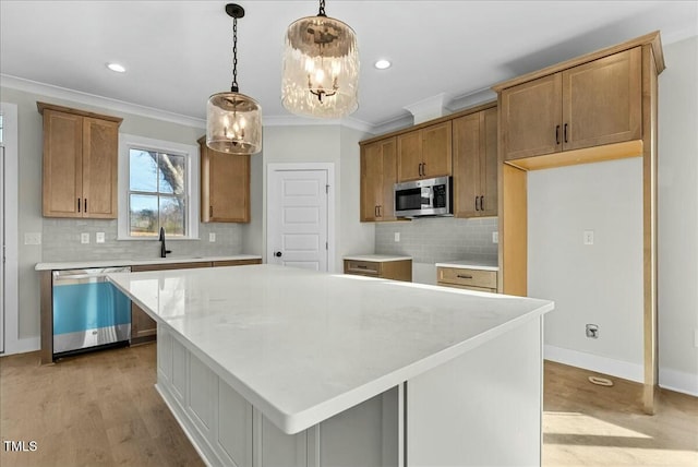 kitchen with stainless steel appliances, a sink, light wood-style floors, brown cabinets, and crown molding