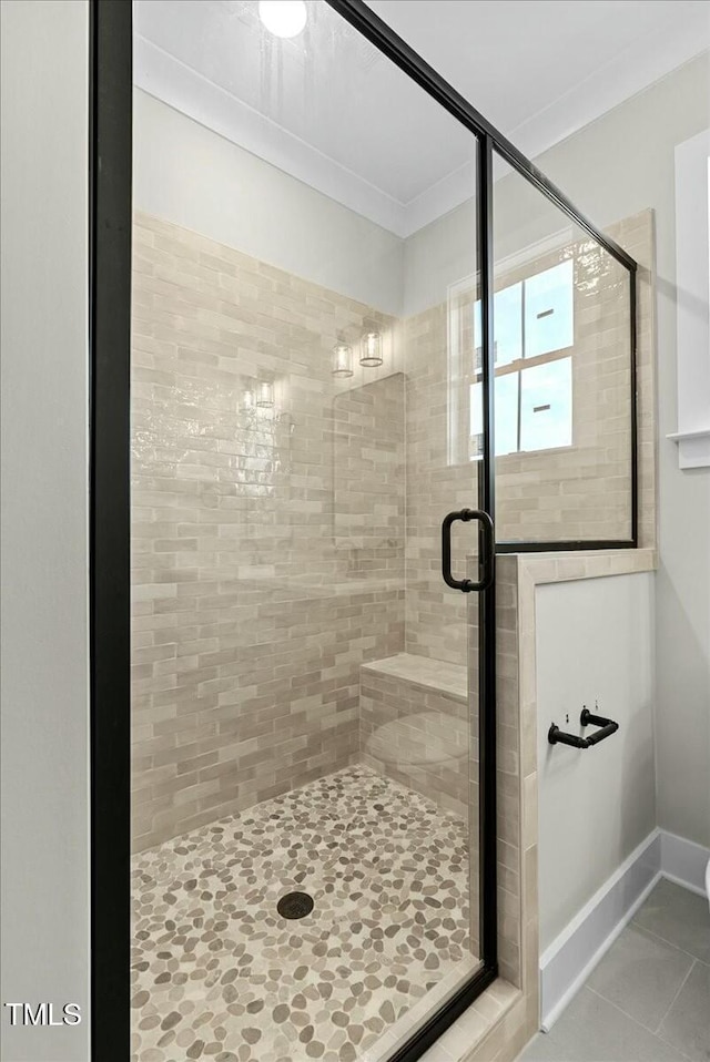 bathroom with tile patterned flooring, a shower stall, and baseboards