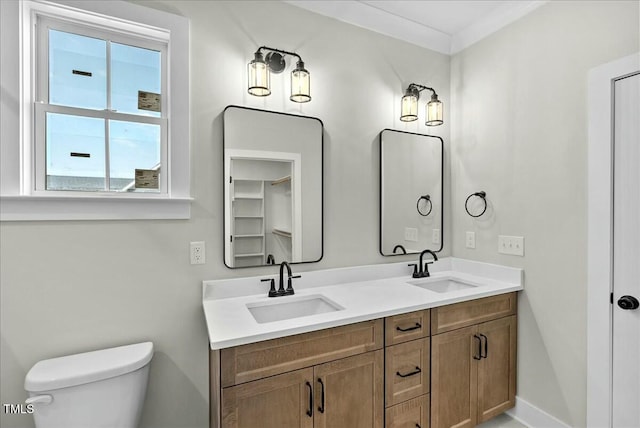 full bathroom with baseboards, a sink, toilet, and double vanity