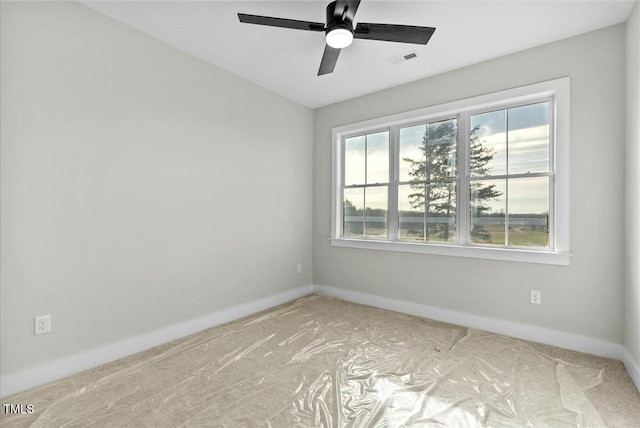 spare room with a ceiling fan, visible vents, and baseboards