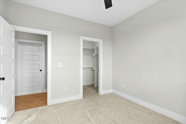 unfurnished bedroom with a ceiling fan, baseboards, a spacious closet, a closet, and carpet