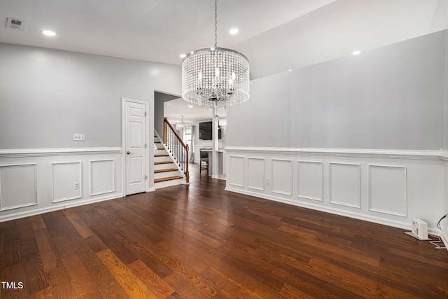 empty room featuring visible vents, wood finished floors, an inviting chandelier, stairs, and recessed lighting