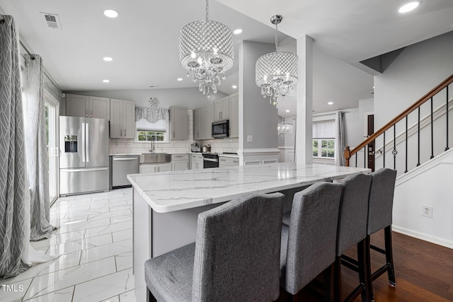 kitchen with a chandelier, stainless steel appliances, visible vents, vaulted ceiling, and gray cabinets