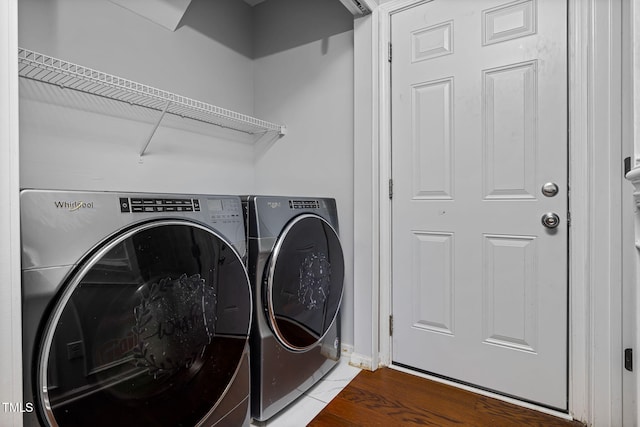 clothes washing area featuring laundry area, wood finished floors, and washer and dryer