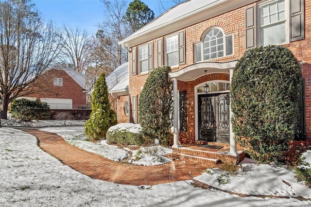 snow covered property entrance with brick siding