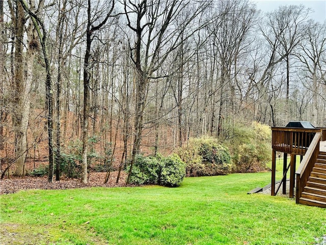 view of yard with a deck, stairway, and a wooded view