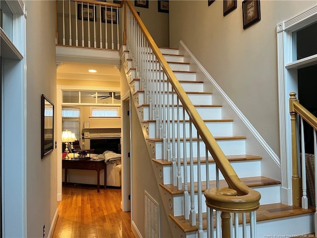 stairway featuring visible vents, a high ceiling, and wood finished floors