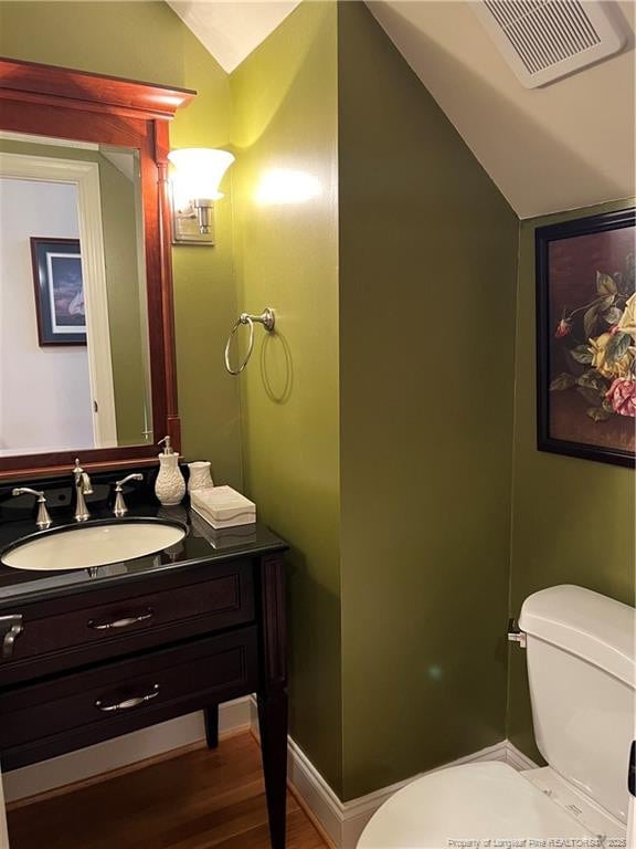 bathroom with vaulted ceiling, toilet, vanity, and visible vents