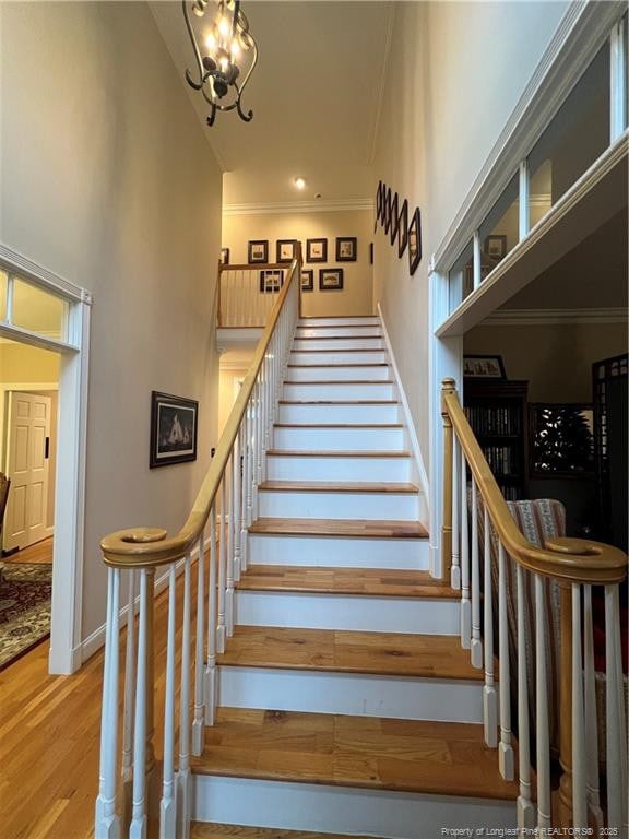 staircase with ornamental molding, baseboards, a high ceiling, and wood finished floors