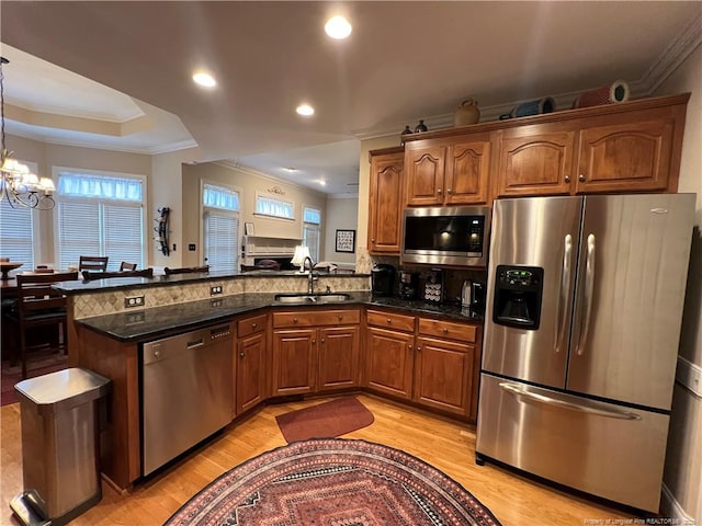 kitchen with a peninsula, brown cabinets, stainless steel appliances, and a sink