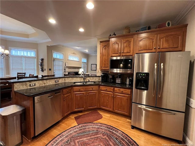 kitchen with a peninsula, light wood finished floors, stainless steel appliances, and a sink