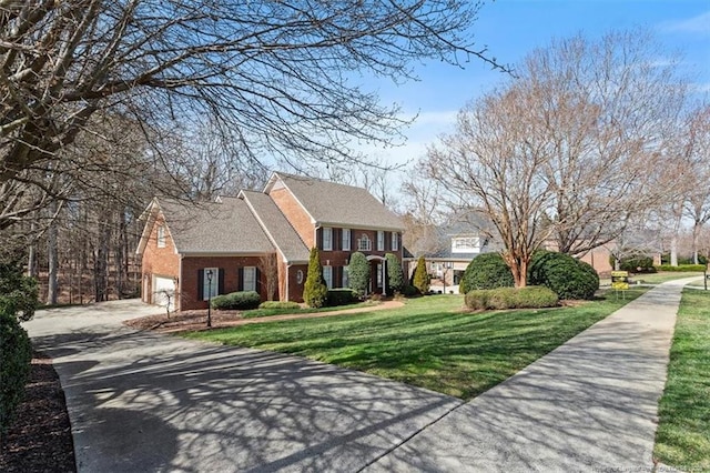 view of front of home featuring brick siding, driveway, an attached garage, and a front lawn