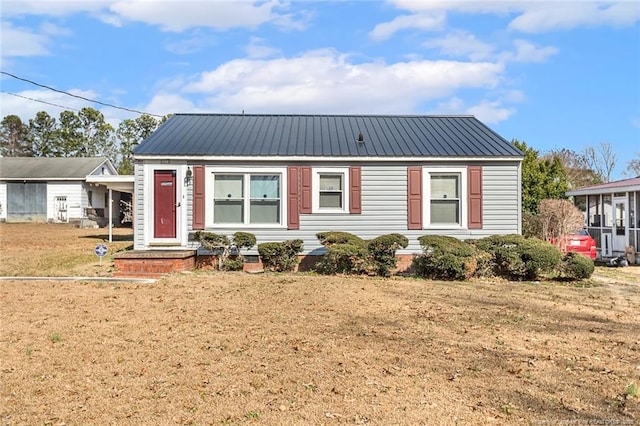 view of front facade featuring metal roof and a front lawn